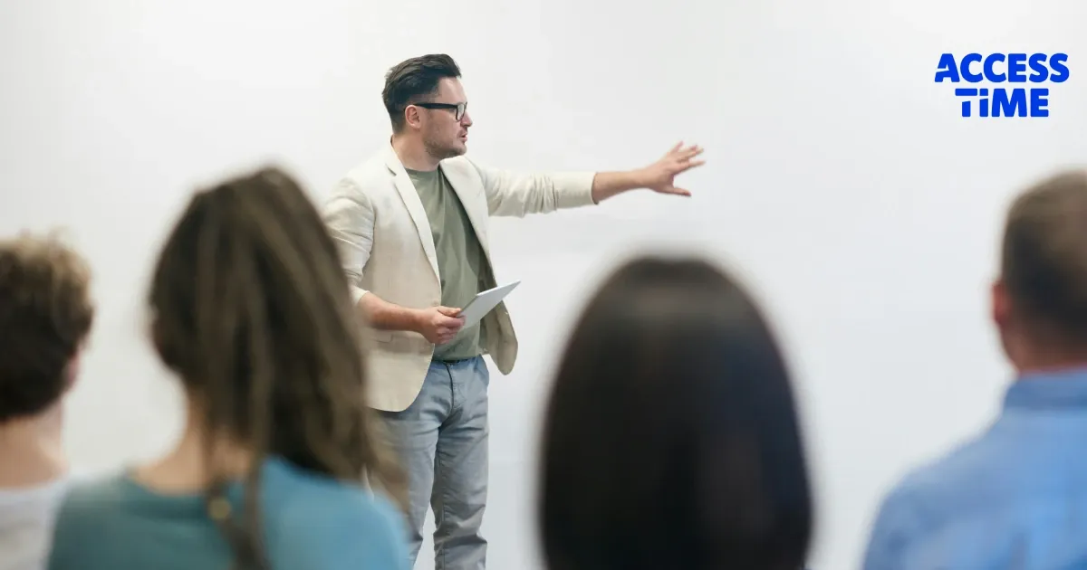 A presenter in front of audience, pointing at the board with his hand
